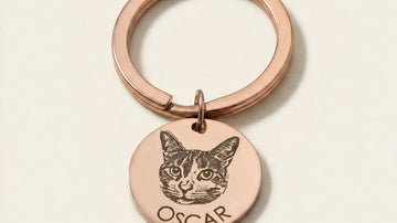 A rose gold keychain with a round pendant featuring a cat's face.