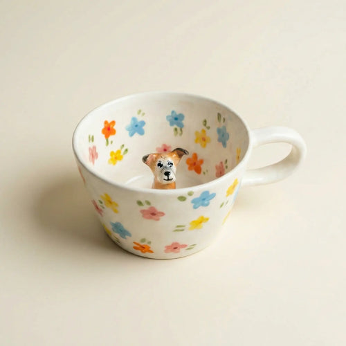 Dog figurine sitting inside floral ceramic mug
