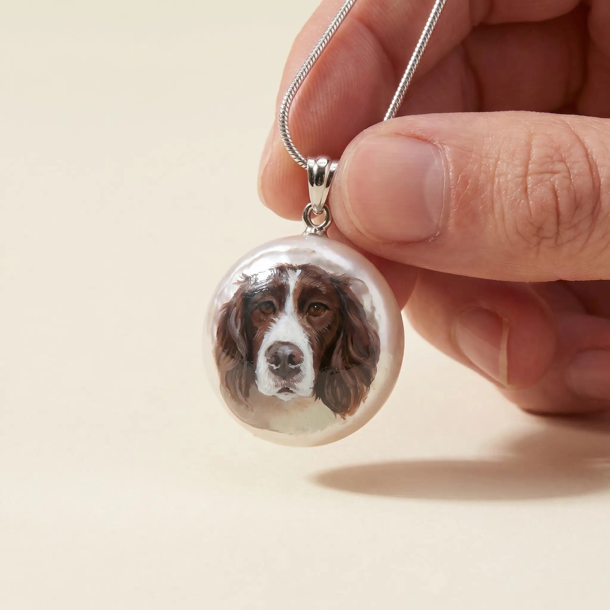 Hand holding round dog portrait pendant