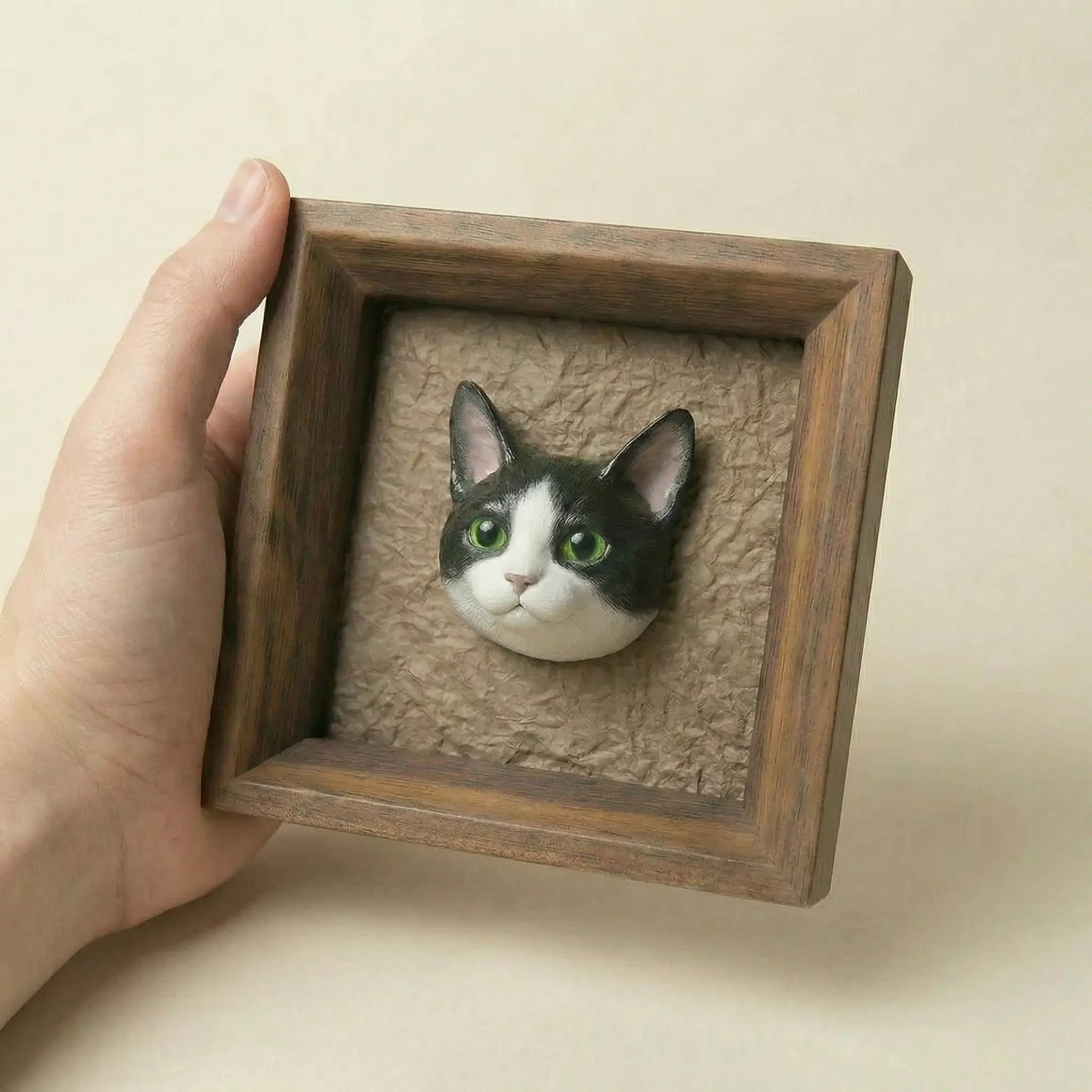 Hand holding framed plaster cat sculpture